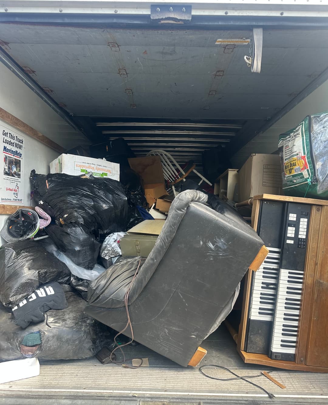 Moving truck loaded with a couch, keyboard, and furniture ready for junk removal disposal